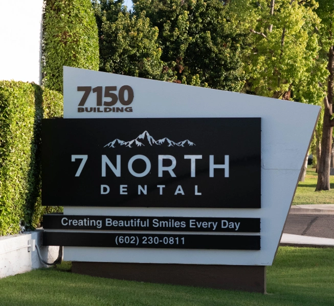7 North Dental outdoor signage displaying practice name, address, and motto in landscaped setting.