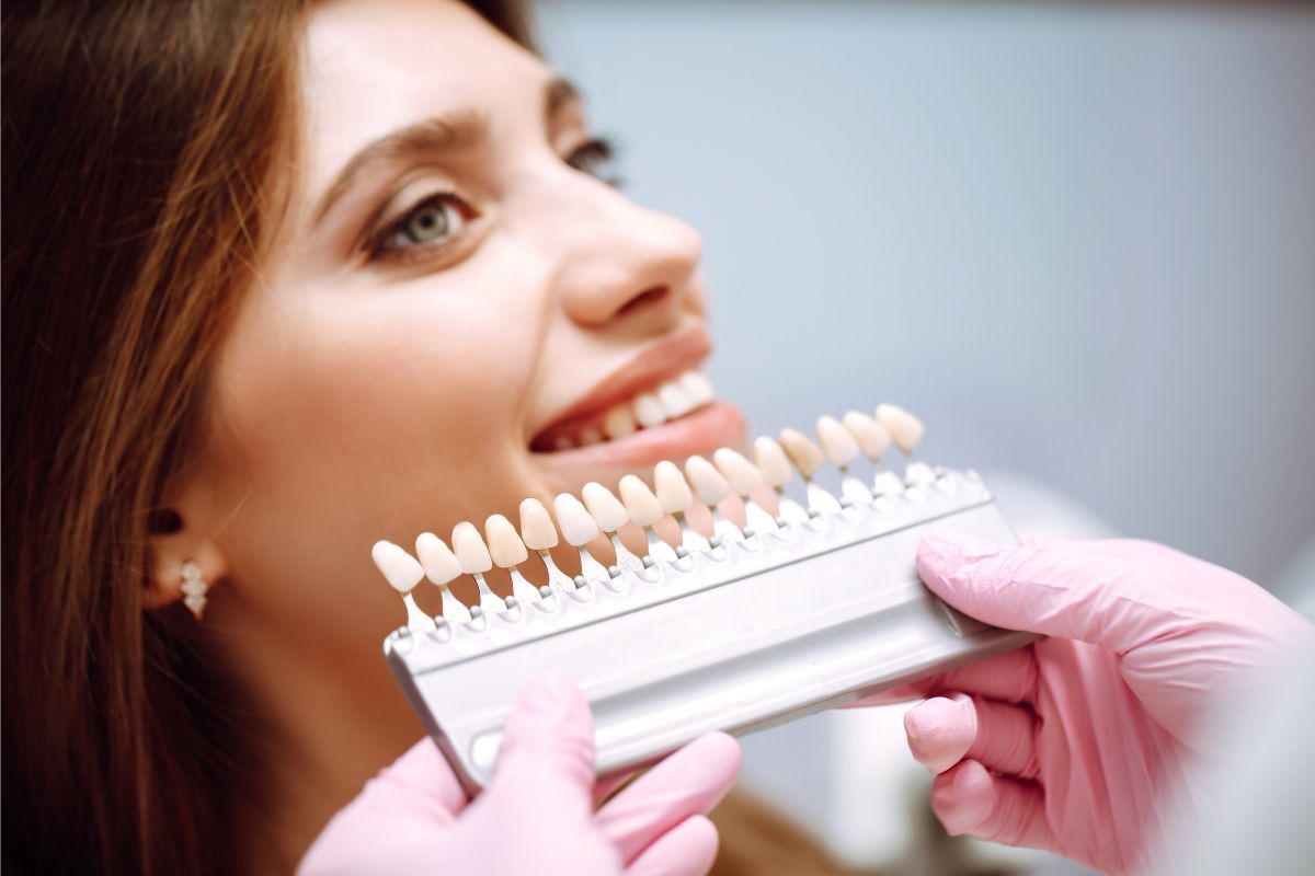 Woman examining dental shade guide showing tooth color options for bonding treatment.